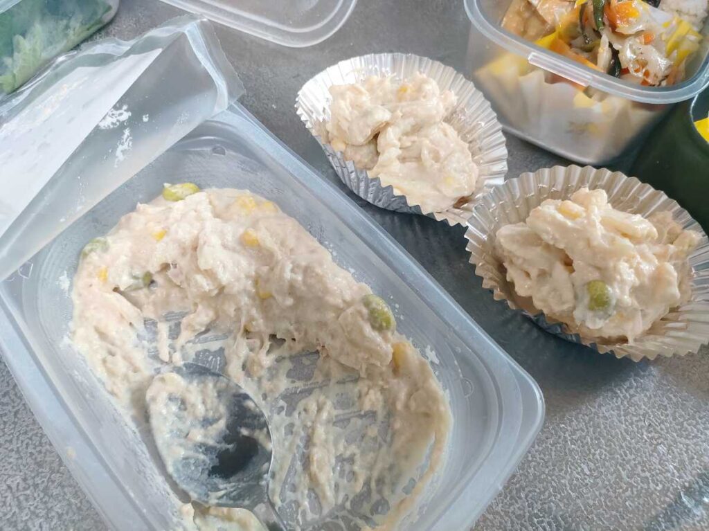 お弁当の隙間にポテトサラダを入れようとしている様子