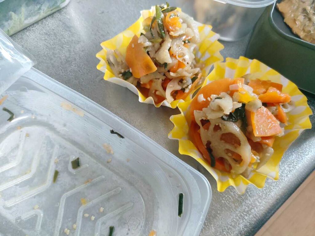 にらとレンコンのきんぴらをおかずカップに入れている様子