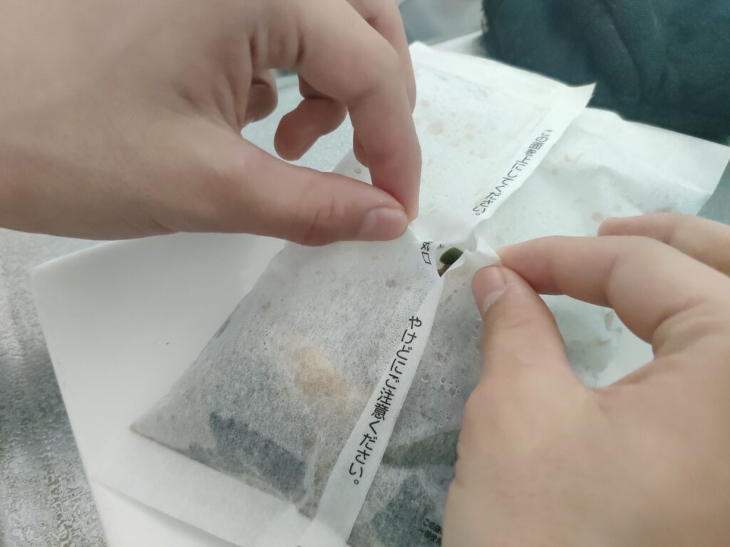 加熱後の紙包みの開封口を確認する様子